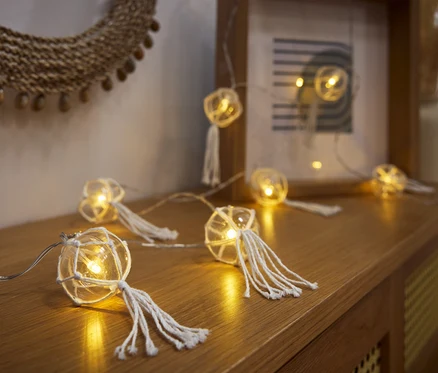 LED-Kugel-Lichterkette leży na drewnianej komodzie.