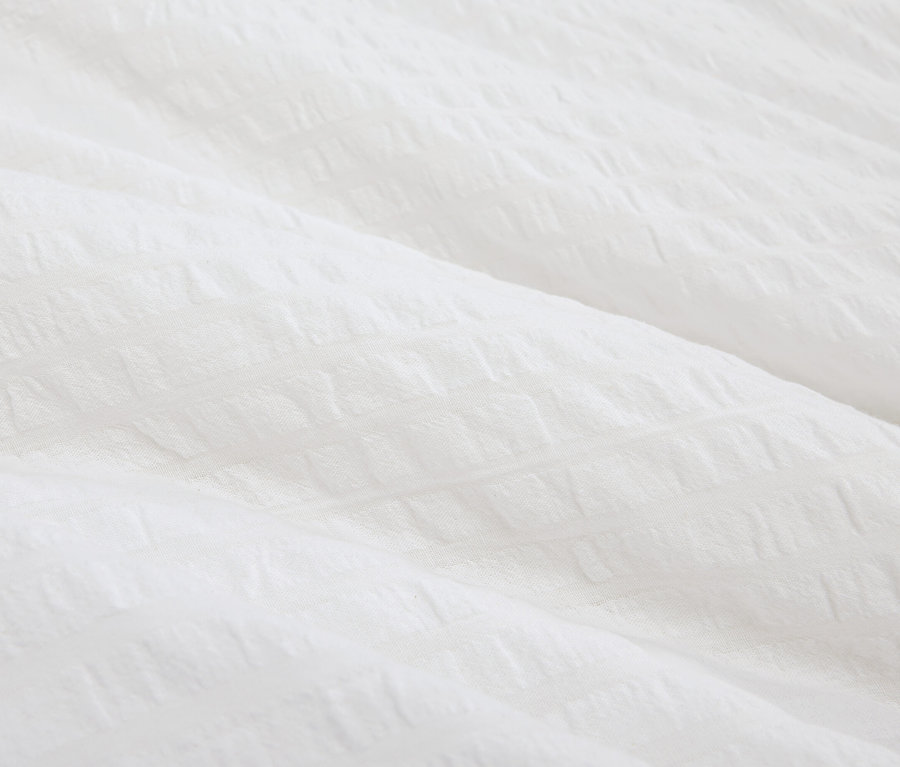 Szczegółowe ujęcie białej, teksturowanej tkaniny.