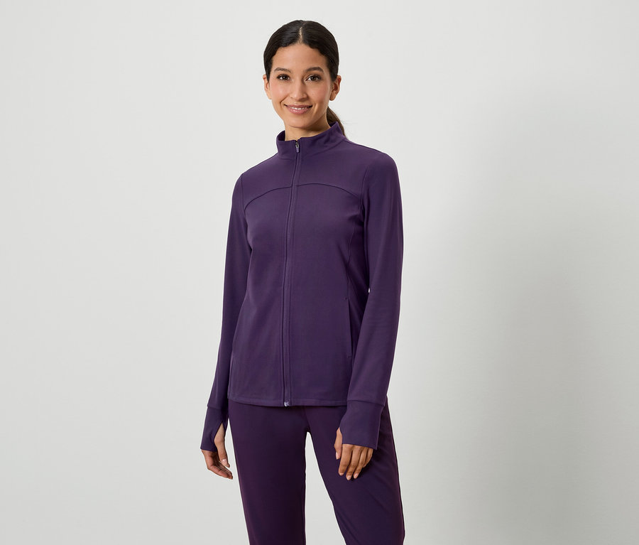 Kobieta pozuje w fioletowym zestawie kurtki i spodni.