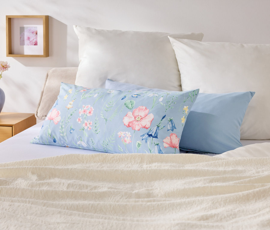 Na łóżku leżą poduszki w różnych kolorach i wzorach.