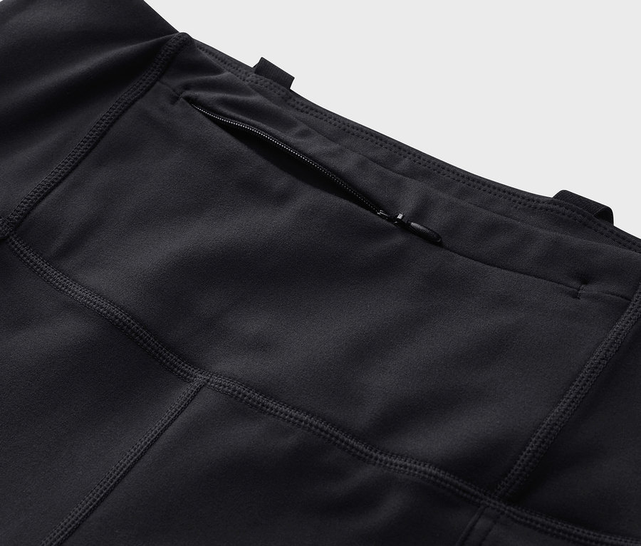 Zbliżenie na czarne legginsy outdoorowe z kieszenią na zamek błyskawiczny.