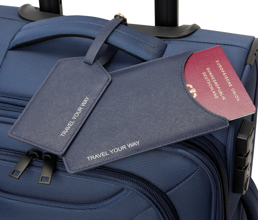 Niebieska walizka na kółkach z okładką na paszport i przywieszką do bagażu.