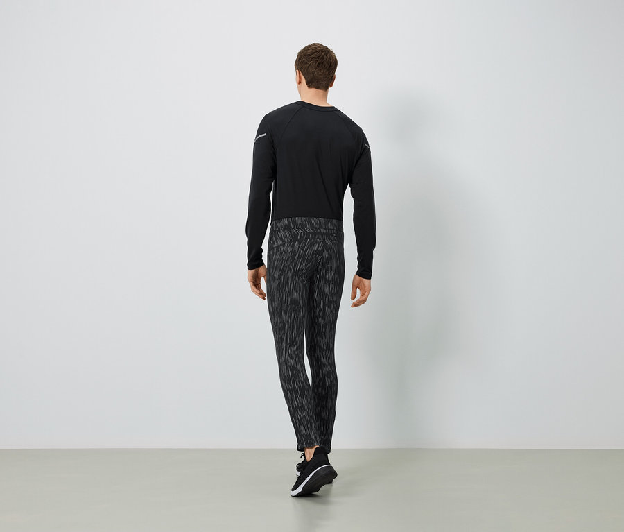 Mężczyzna w czarnej koszulce z długim rękawem i wzorzystych spodniach, widok z tyłu.