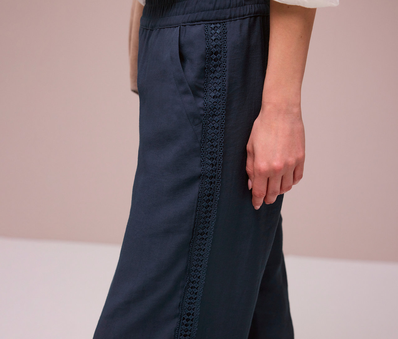 Kobieta ma na sobie granatowe spodnie Street One „Emee” z ozdobnymi paskami.