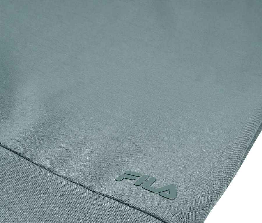 Zbliżenie na jasnoniebiesko-zieloną odzież z logo FILA.
