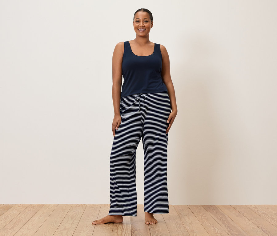 Kobieta ma na sobie niebieską koszulkę i spodnie w paski.