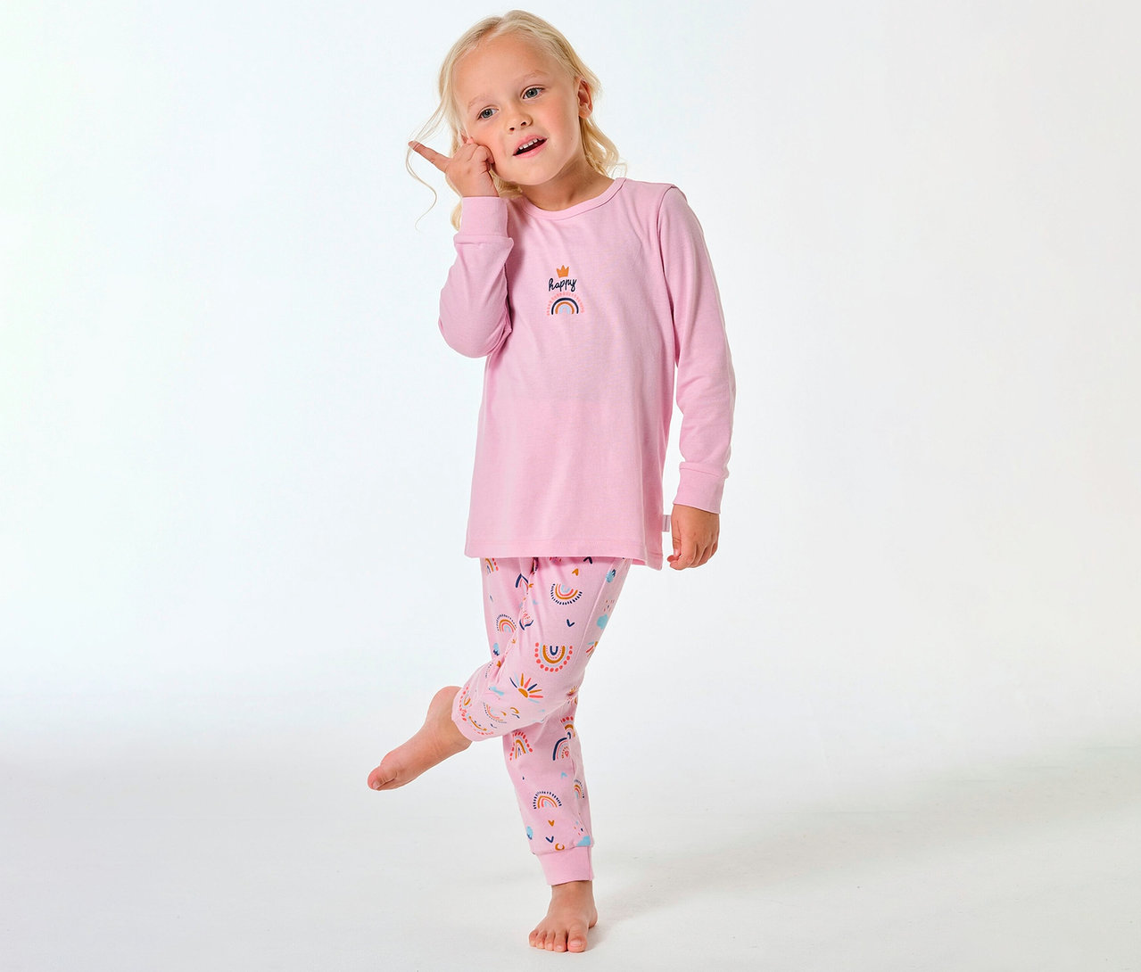 Dziewczynka w długiej piżamie dziecięcej SCHIESSER z tęczowym wzorem na spodniach i górze.