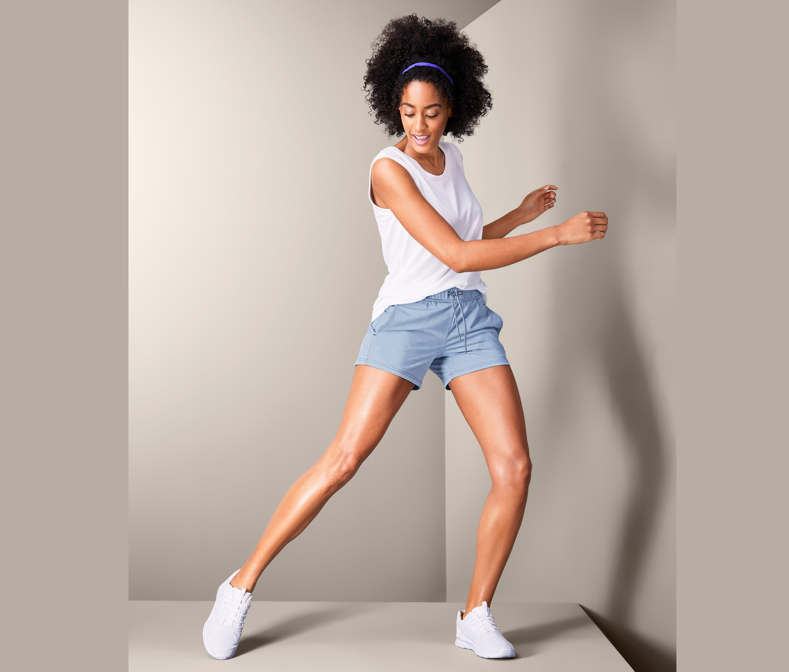 Kobieta pozuje na scenie w krótkich spodenkach sportowych.