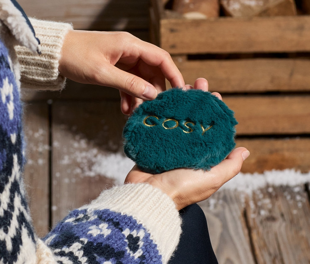 Kobieta trzyma w dłoni dwa kieszonkowe ogrzewacze.