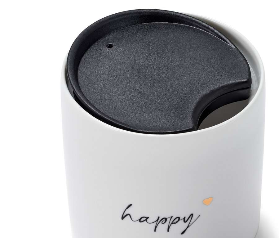 Zbliżenie na biały ceramiczny kubek z czarną pokrywką i napisem Happy.