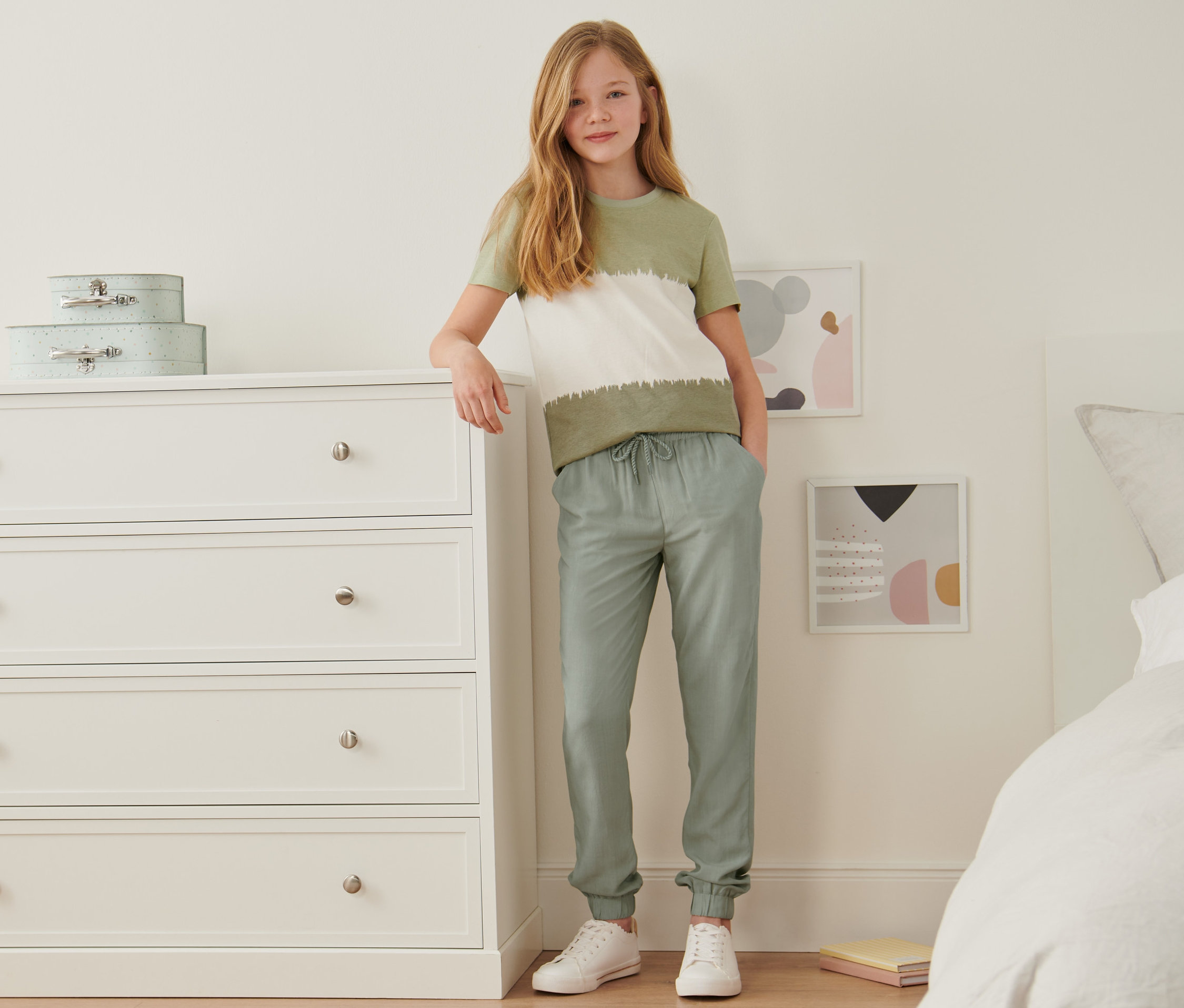 Dziewczyna stoi w pokoju i ma na sobie spodnie na gumce z wiskozy ECOVERO™.