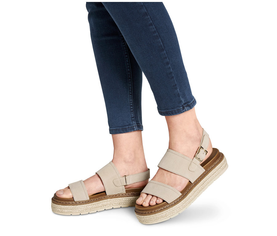 Stopy w jeansach noszą sandały skórzane na platformie.