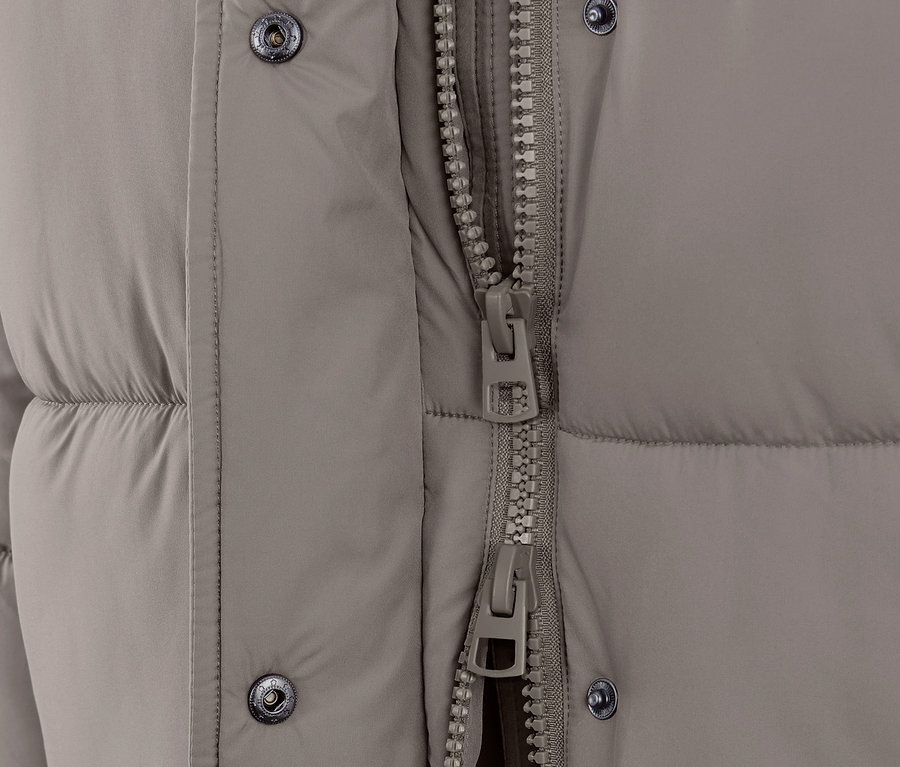 Zbliżenie na szarobeżowy płaszcz pikowany z kapturem i zamkiem błyskawicznym.