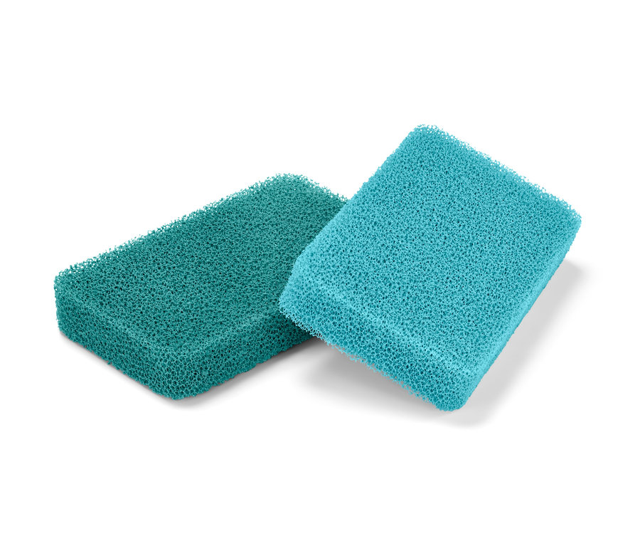 Dwie gąbki silikonowe, jedna zielona i jedna niebieska, leżą na białym tle.