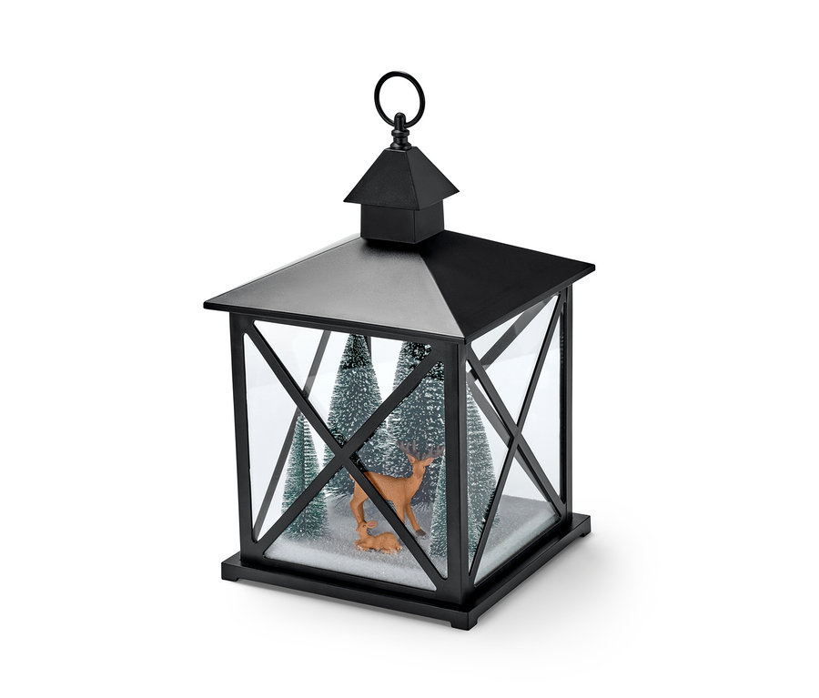 Czarna latarnia dekoracyjna LED z dwiema figurkami jeleni i trzema małymi, ośnieżonymi drzewkami w środku.