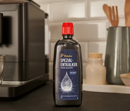 Czarna butelka specjalistycznego odkamieniacza durgol® 400 ml stoi na blacie obok ekspresu do kawy.