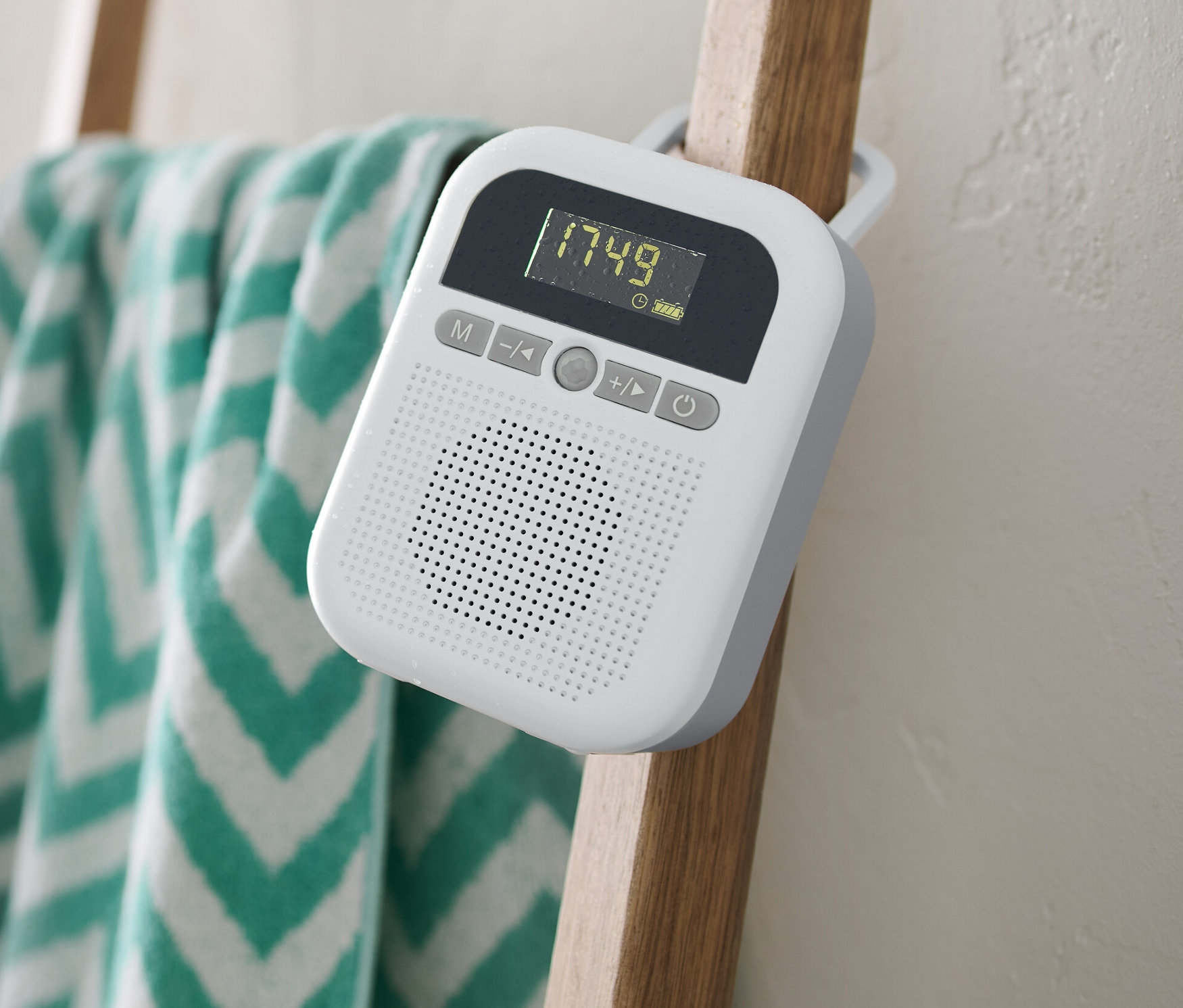 Białe radio łazienkowe wisi na drewnianej drabinie, na której wisi ręcznik.