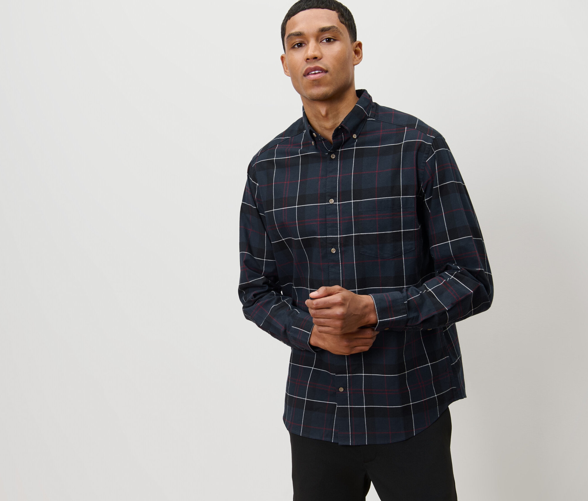 Mężczyzna pozuje w granatowej koszuli flanelowej.
