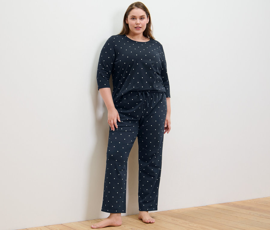 Kobieta stoi w piżamie w kropki.