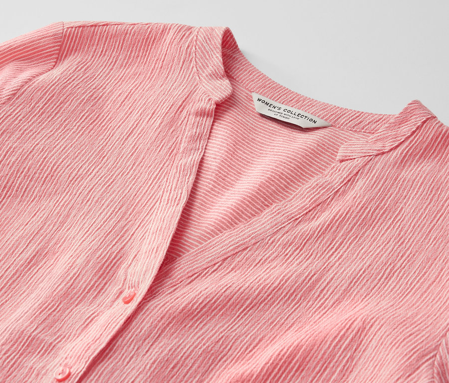 Zbliżenie na koralową tunikę w paski.