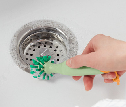 Kobieta czyści zlew szczotką uniwersalną.