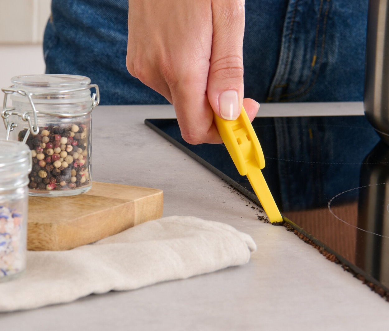 Kobieta czyści krawędź płyty ceramicznej szczotką do czyszczenia 3 w 1.