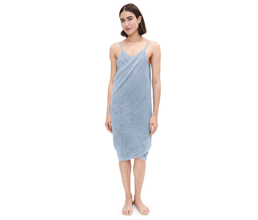 Kobieta stoi i ma na sobie jasnoniebieską sukienkę ręcznikową.