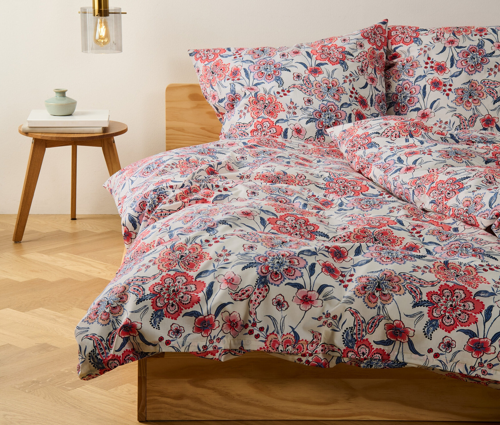 Zbliżenie na kremową pościel z bawełny renforcé w rozmiarze niestandardowym i standardowym z kwiatowym wzorem na łóżku.