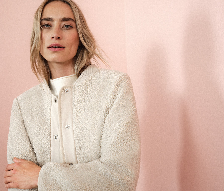 Kobieta ma na sobie kremową kurtkę.