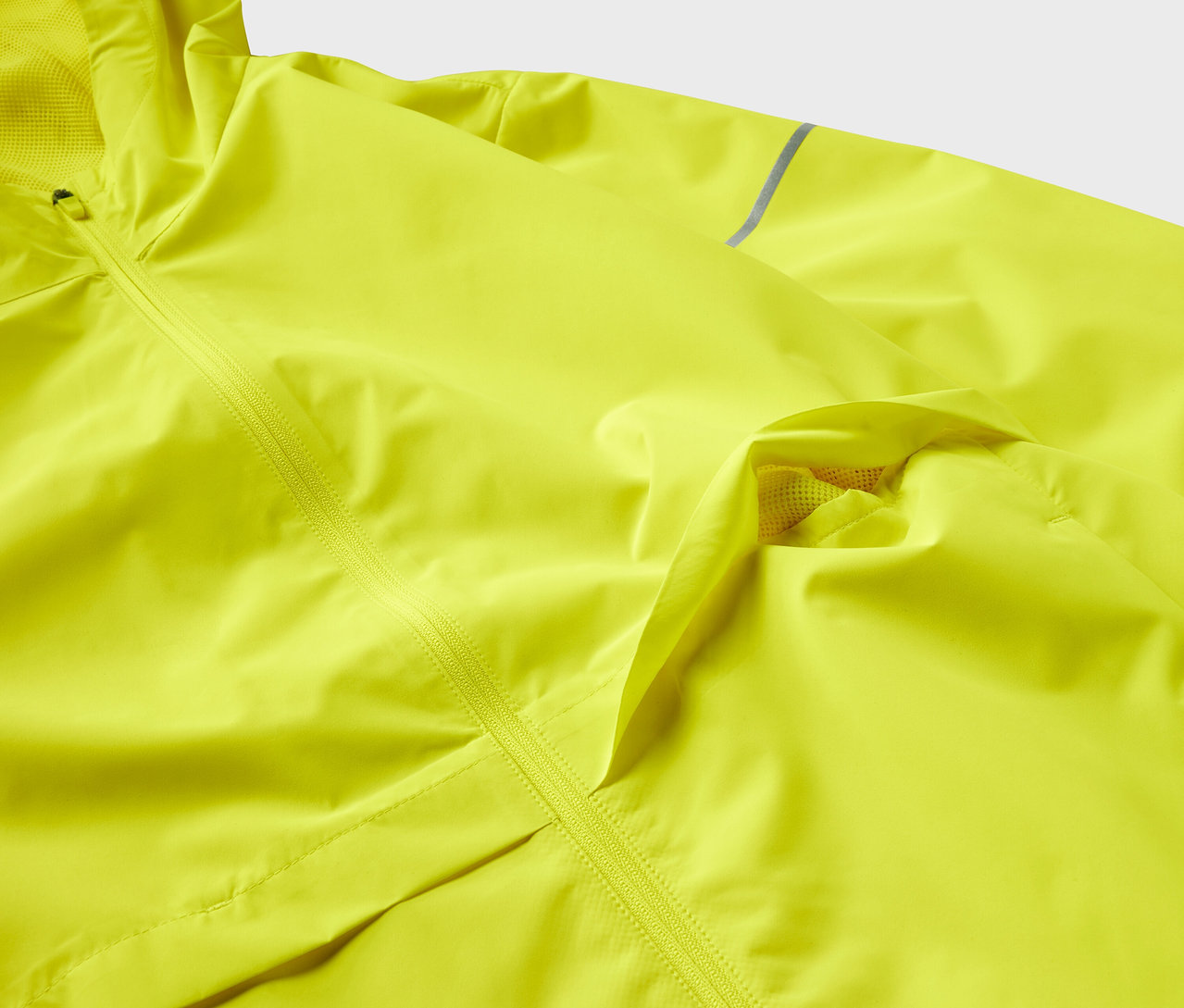 Zbliżenie na żółtą kurtkę z teksturą i zamkiem błyskawicznym.