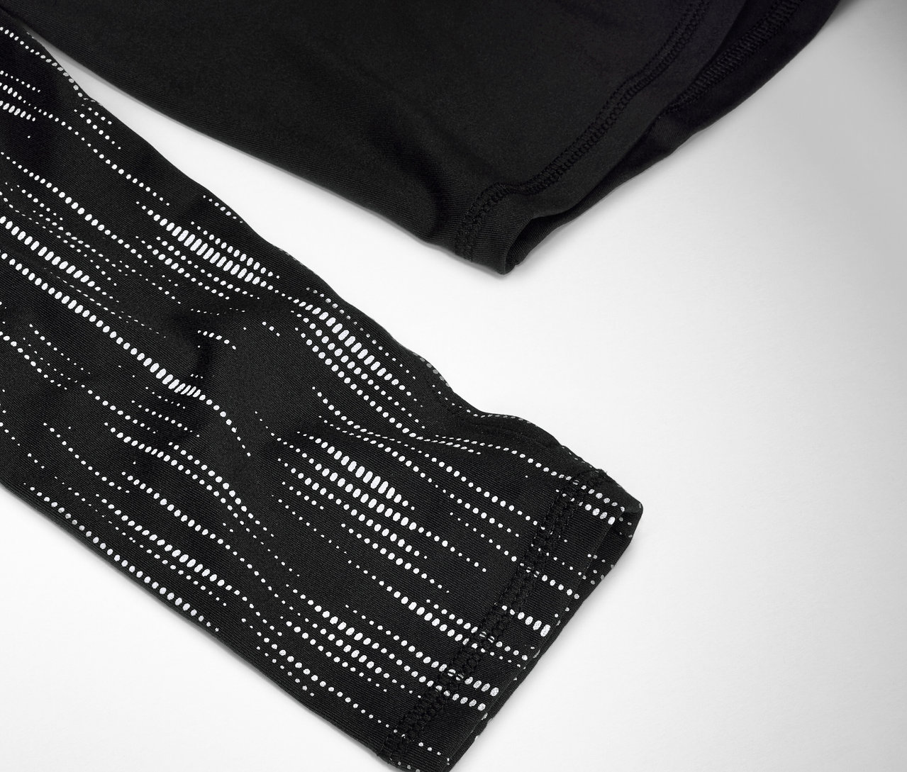 Zbliżenie czarnej koszulki z długim rękawem z białym wzorem w kropki na rękawie.