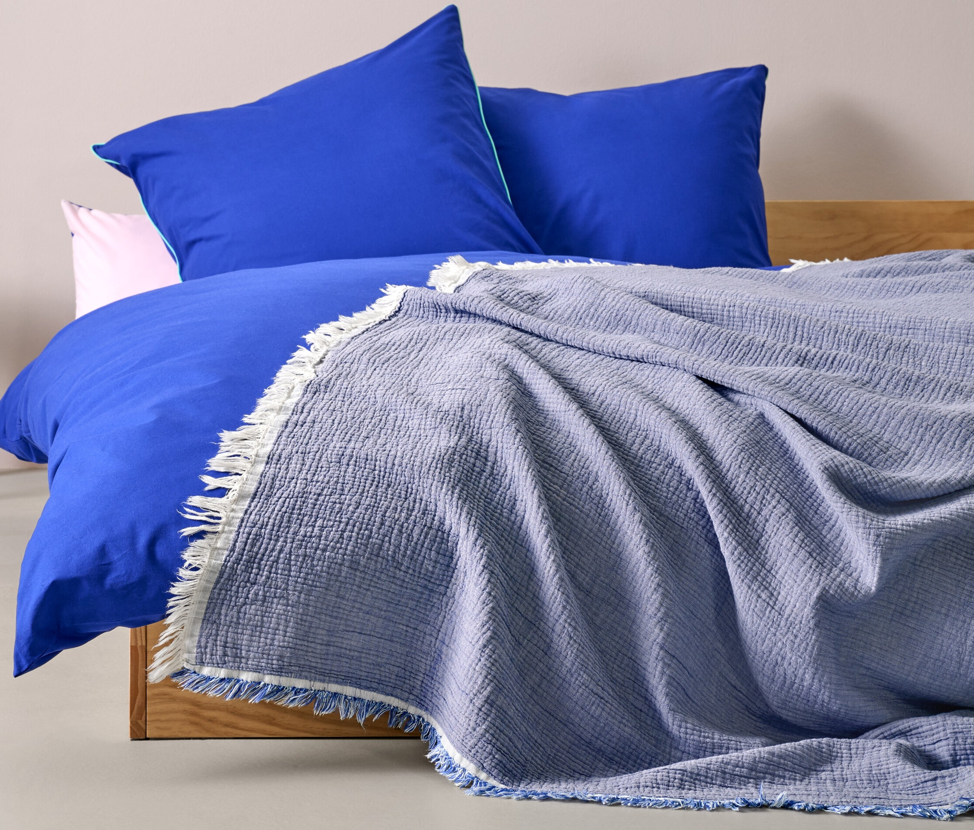 Na łóżku leży niebieska narzuta na łóżko o wymiarach 220 x 240 cm.