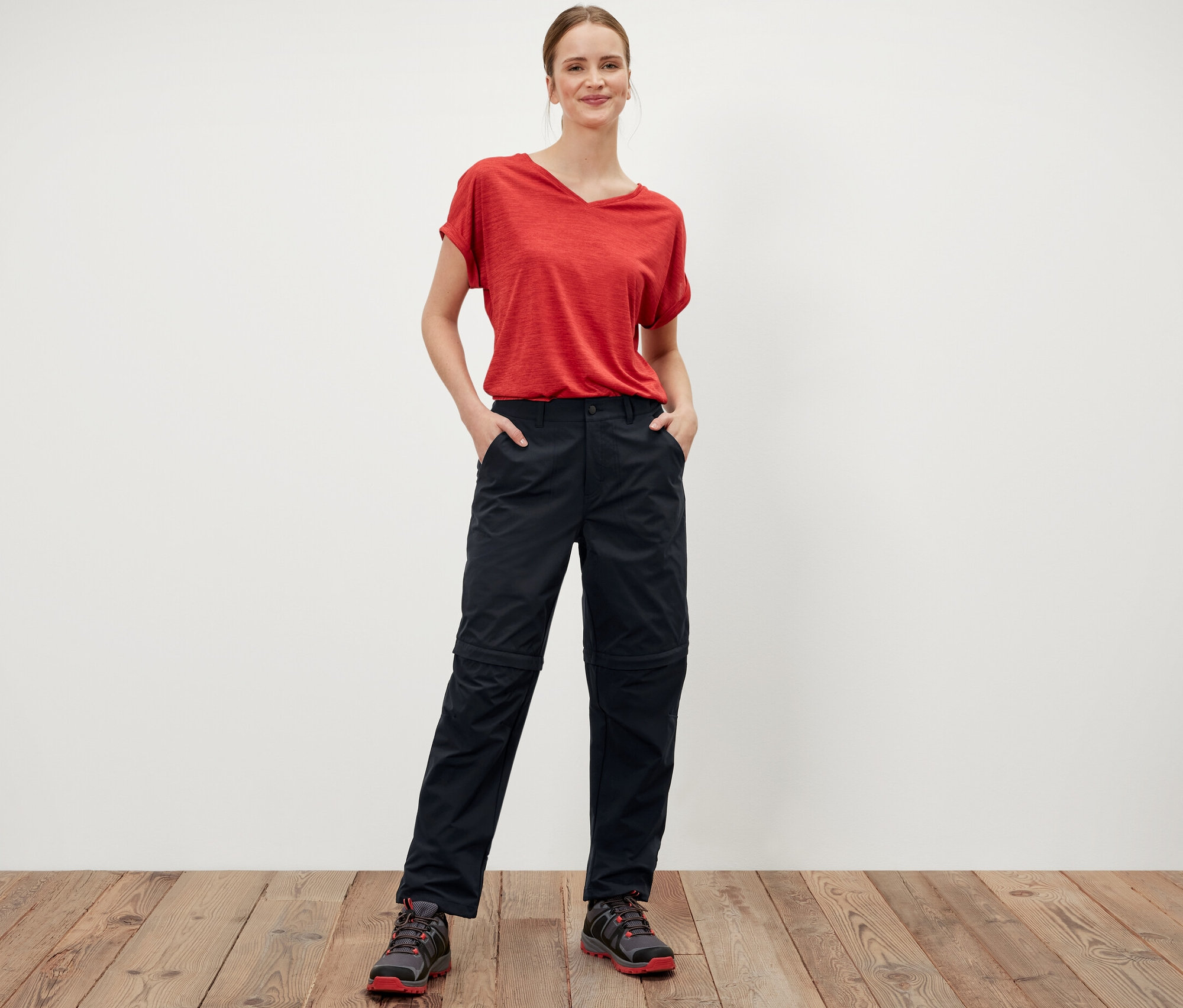 Kobieta stoi z rękami w kieszeniach czarnych spodni funkcyjnych 2 w 1.