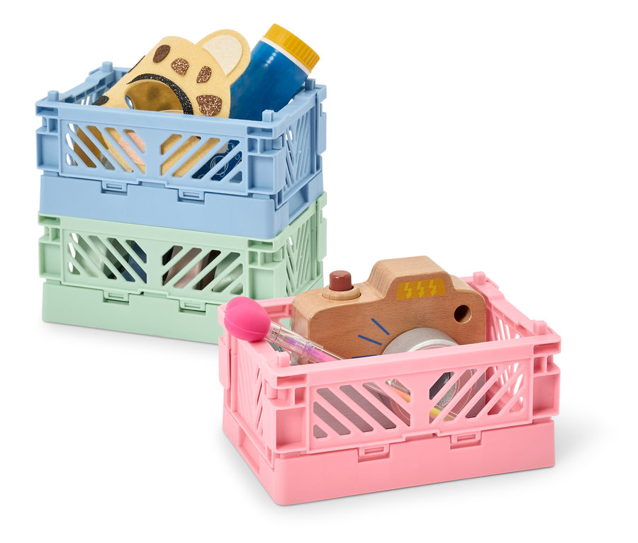 Stos trzech plastikowych skrzynek w różnych kolorach, zawierających zabawki.