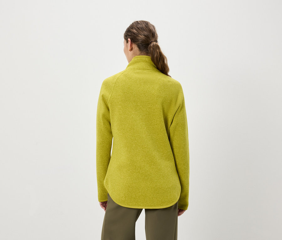 Widok z tyłu kobiety z włosami związanymi w koński ogon, ubranej w żółto-zielony polarowy pulower i oliwkowozielone spodnie.