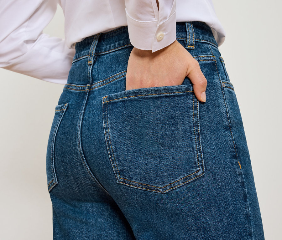 Widok z tyłu na kobietę z ręką w kieszeni niebieskich Mom Jeans – Fit »Nyla«.