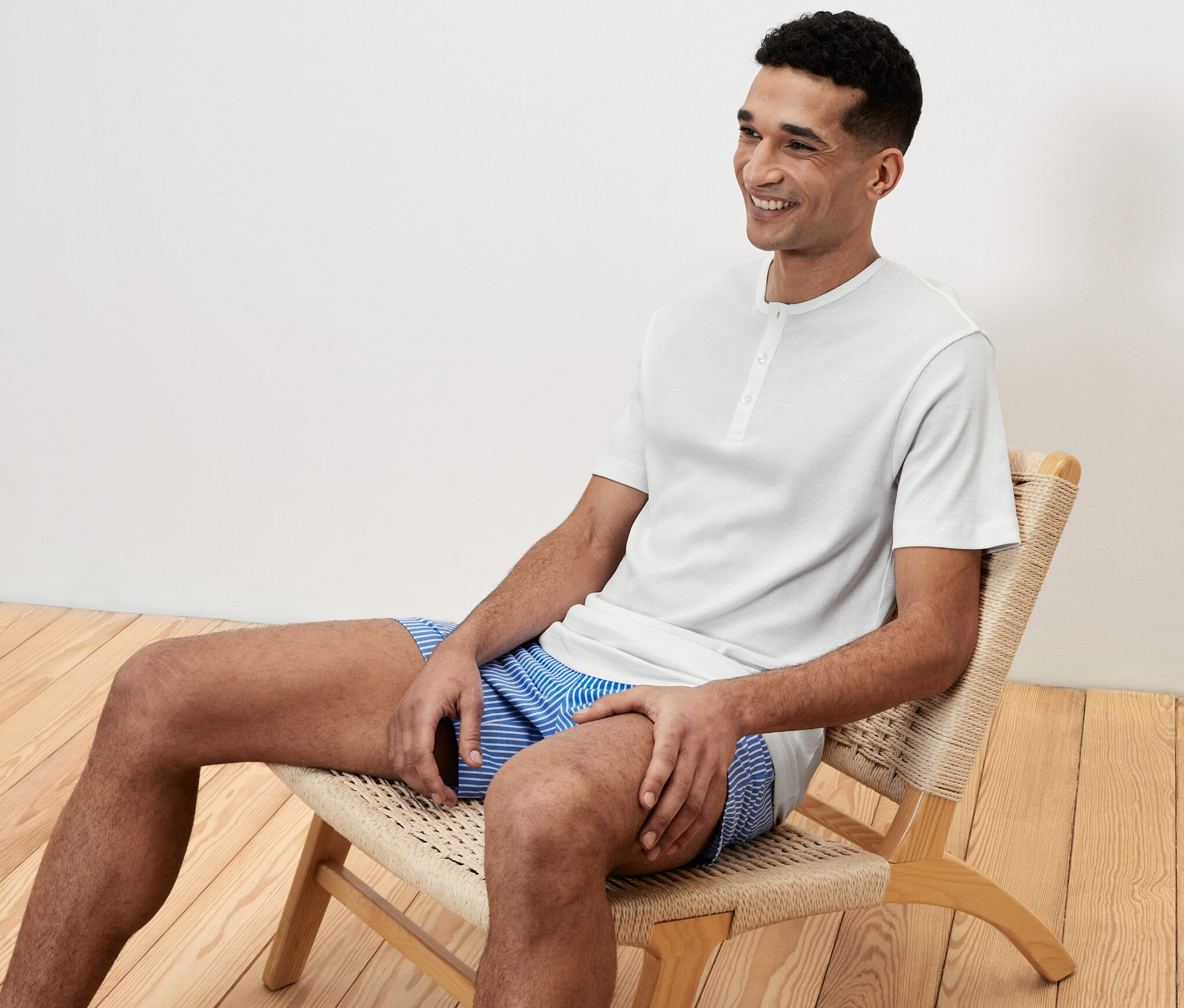 Mężczyzna siedzi na krześle w piżamie i uśmiecha się.