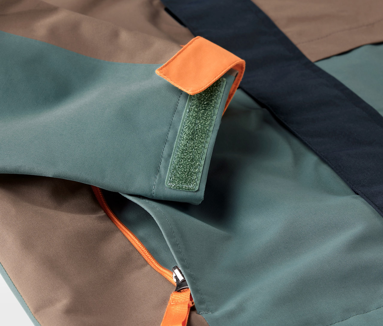 Zbliżenie na kurtkę outdoorową z kieszenią na zamek i mankietem zapinanym na rzep.