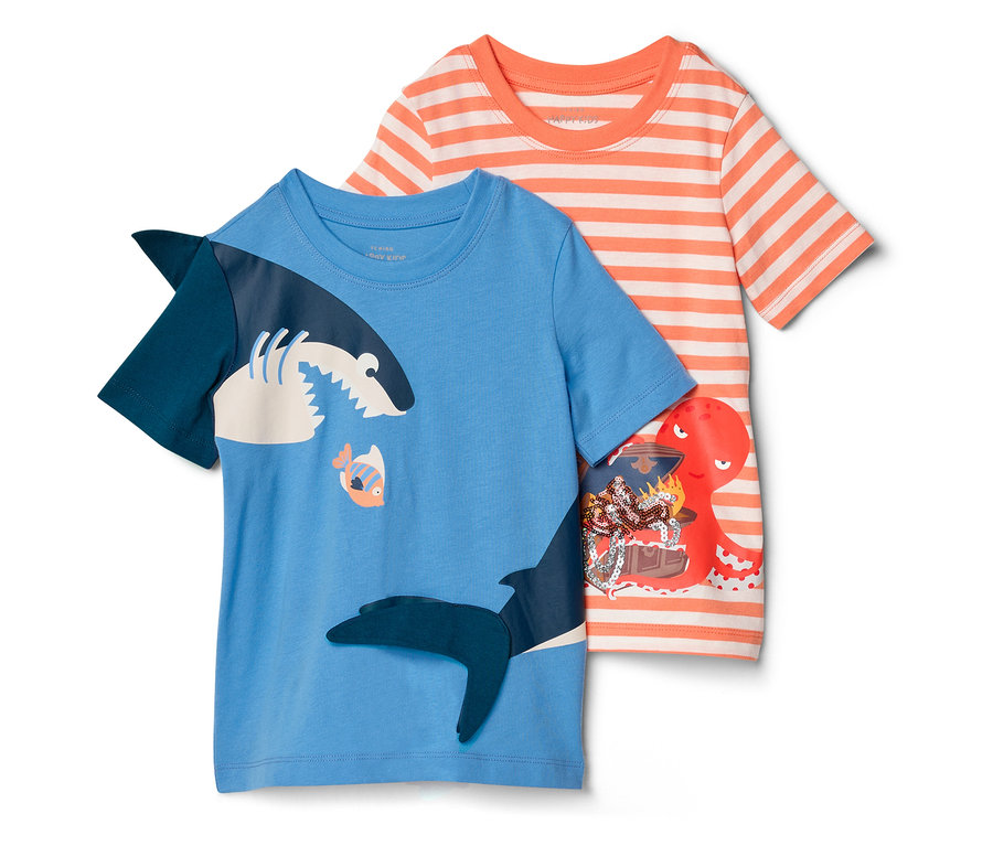 Dwa dziecięce T-shirty leżą obok siebie: niebieski z motywem rekina i pomarańczowo-biały w paski z ośmiornicą i skrzynią skarbów.