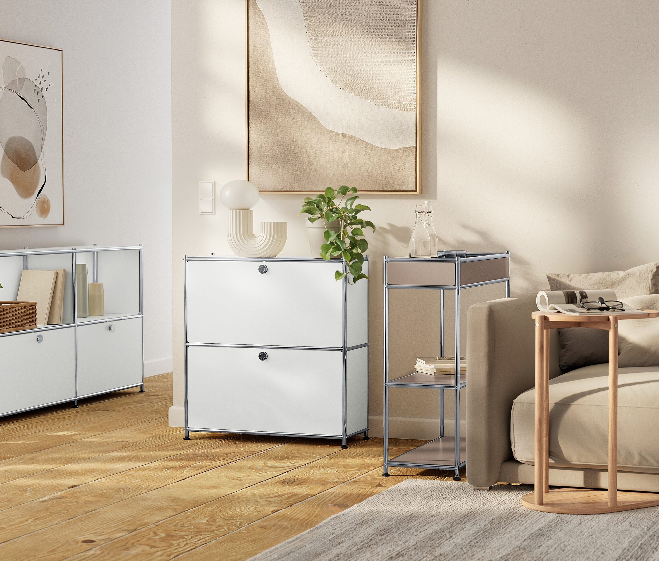 Salon z białymi modułowymi elementami do przechowywania, beżową sofą i neutralnymi dziełami sztuki.