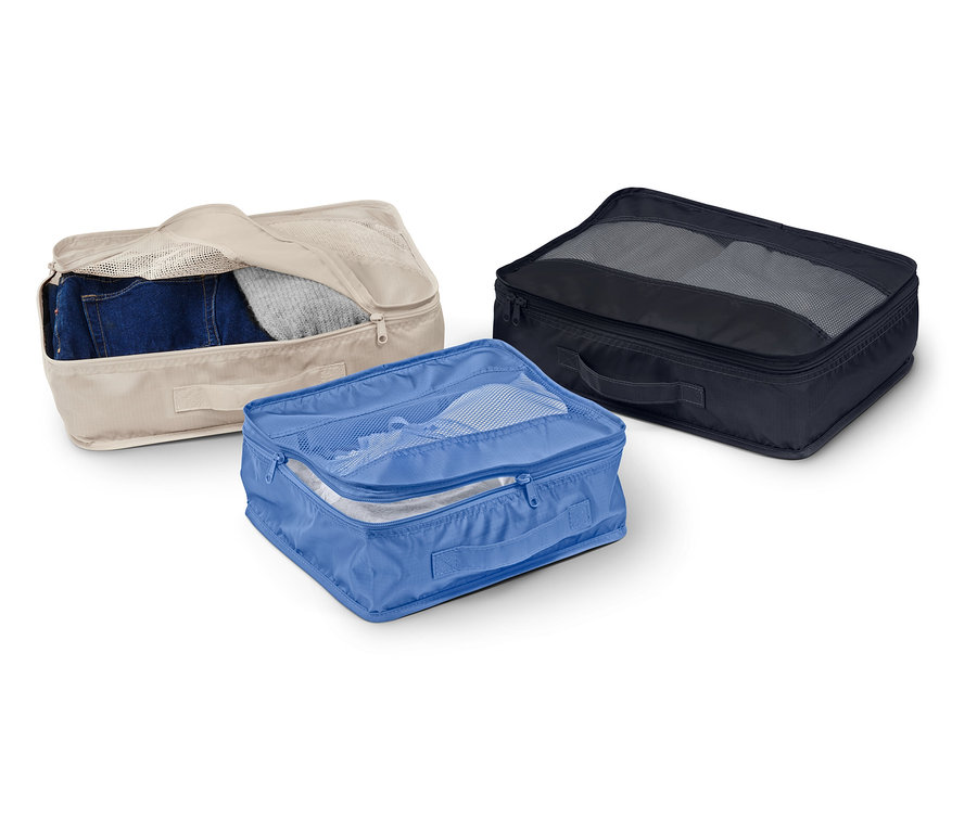 Trzy materiałowe pudełka-organizery w kolorach beżowym, niebieskim i czarnym leżą na białym tle.