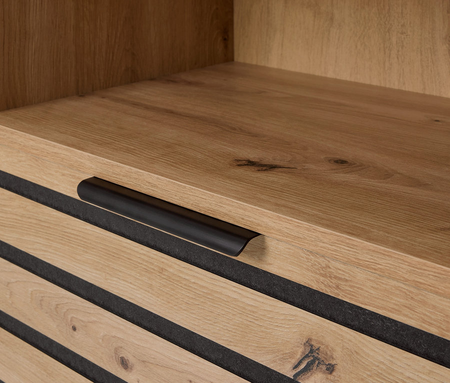 Zbliżenie drewnianej szafki z szufladami i czarnymi uchwytami.