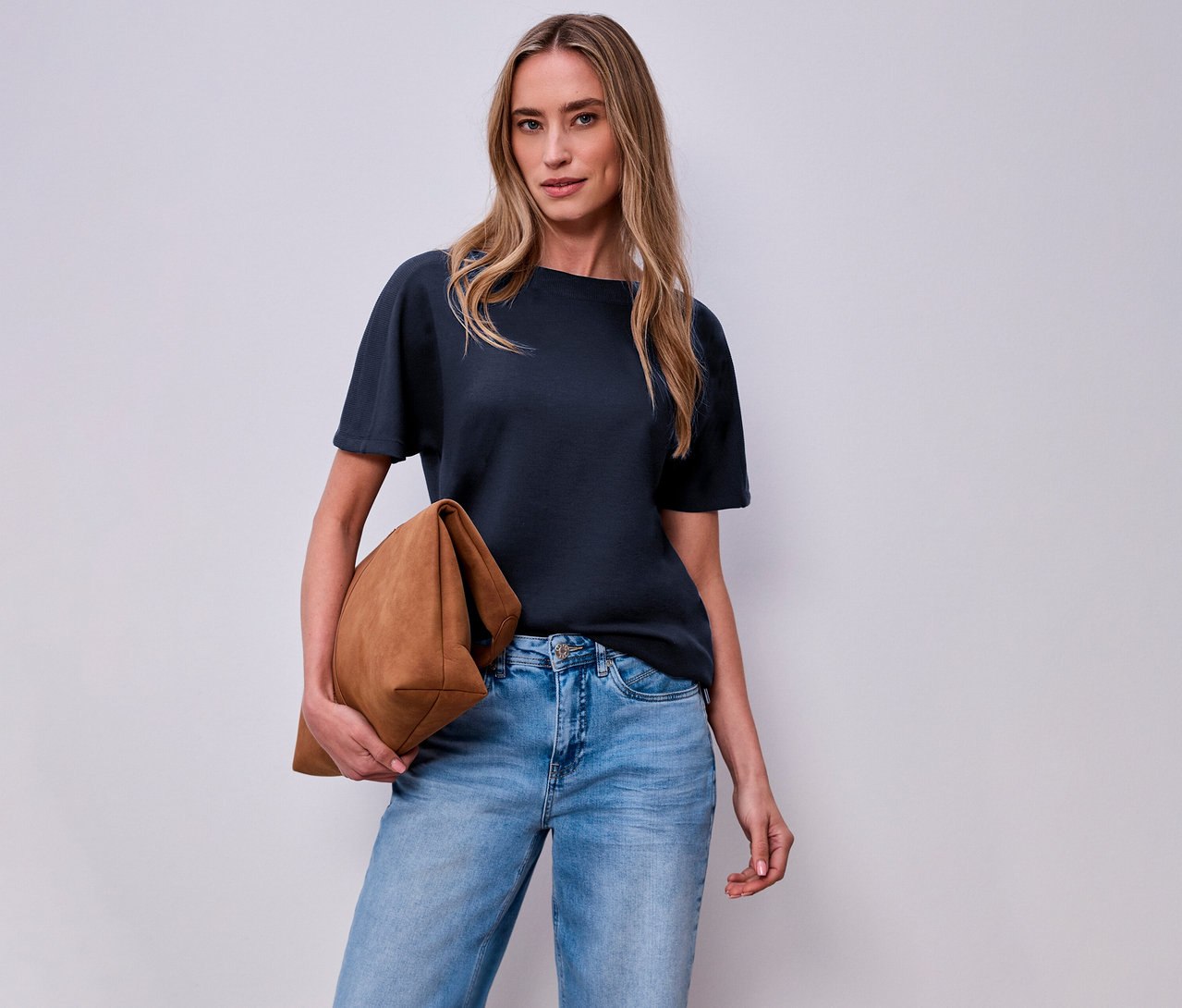 Kobieta z brązową torbą i granatową koszulką Street One na białym tle.