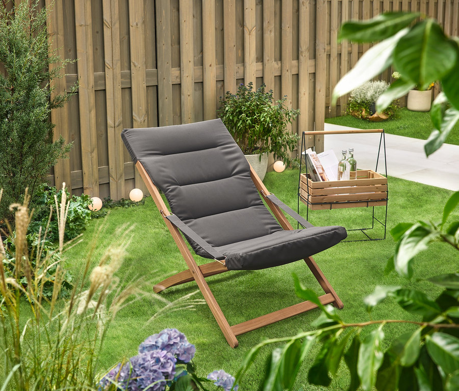 Na zielonym trawniku stoi skrzynka na zioła z uchwytem do przenoszenia »Elin« obok leżaka.