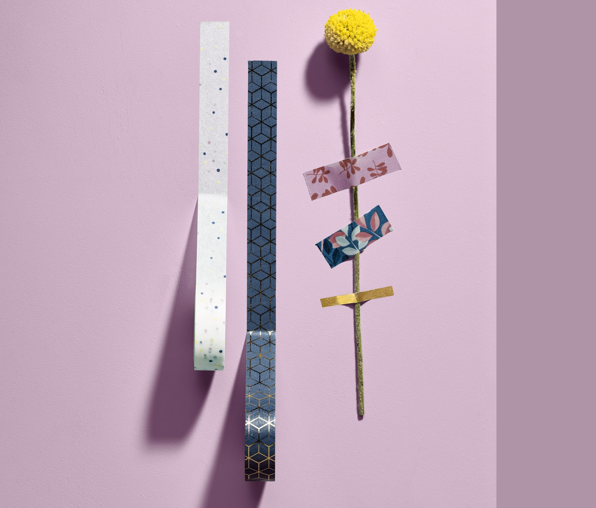 Dwie rolki ozdobnych taśm klejących, 10 sztuk, i żółty kwiat z taśmami klejącymi na łodydze.