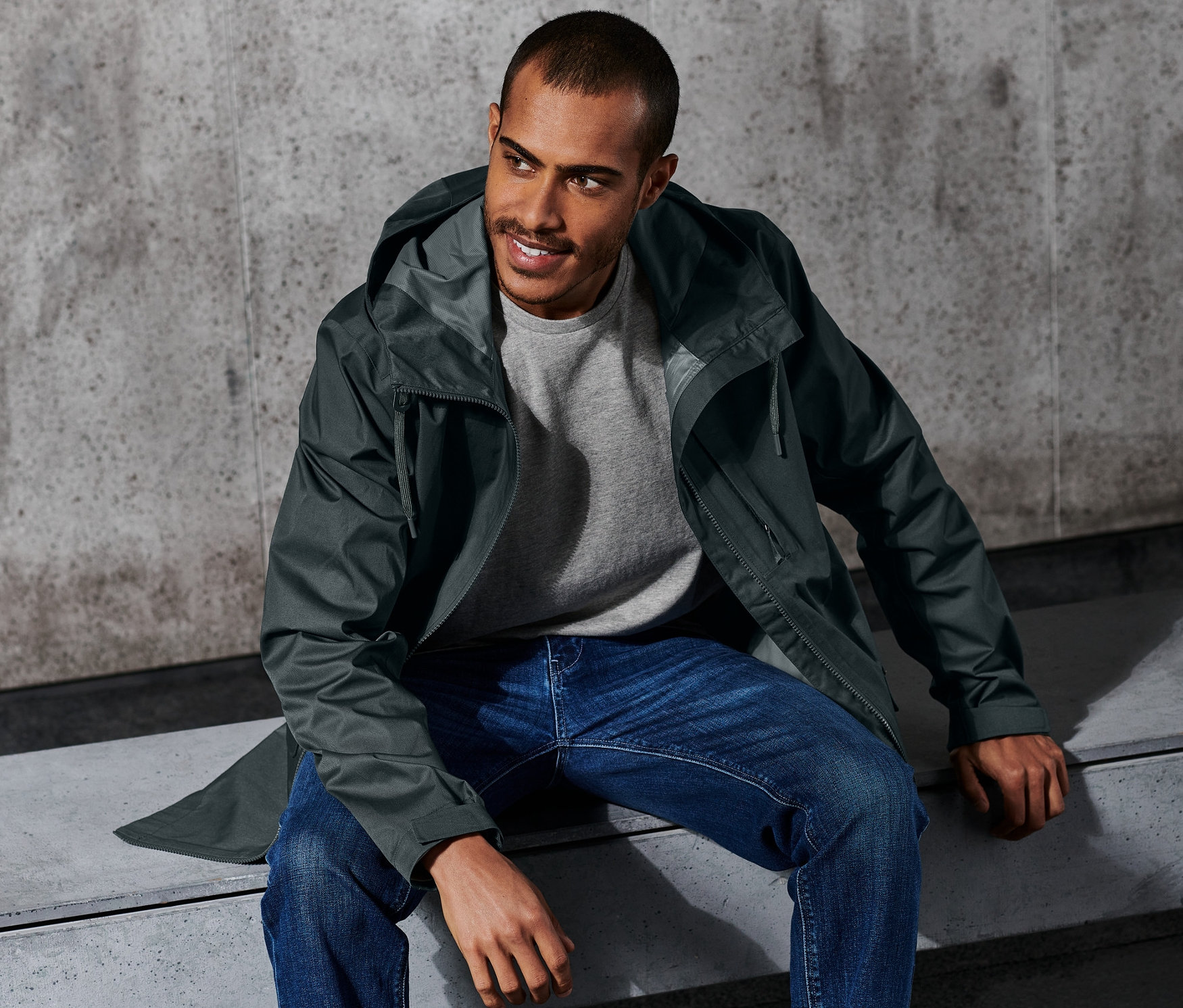 Mężczyzna siedzi na ławce w kurtce trekkingowej.