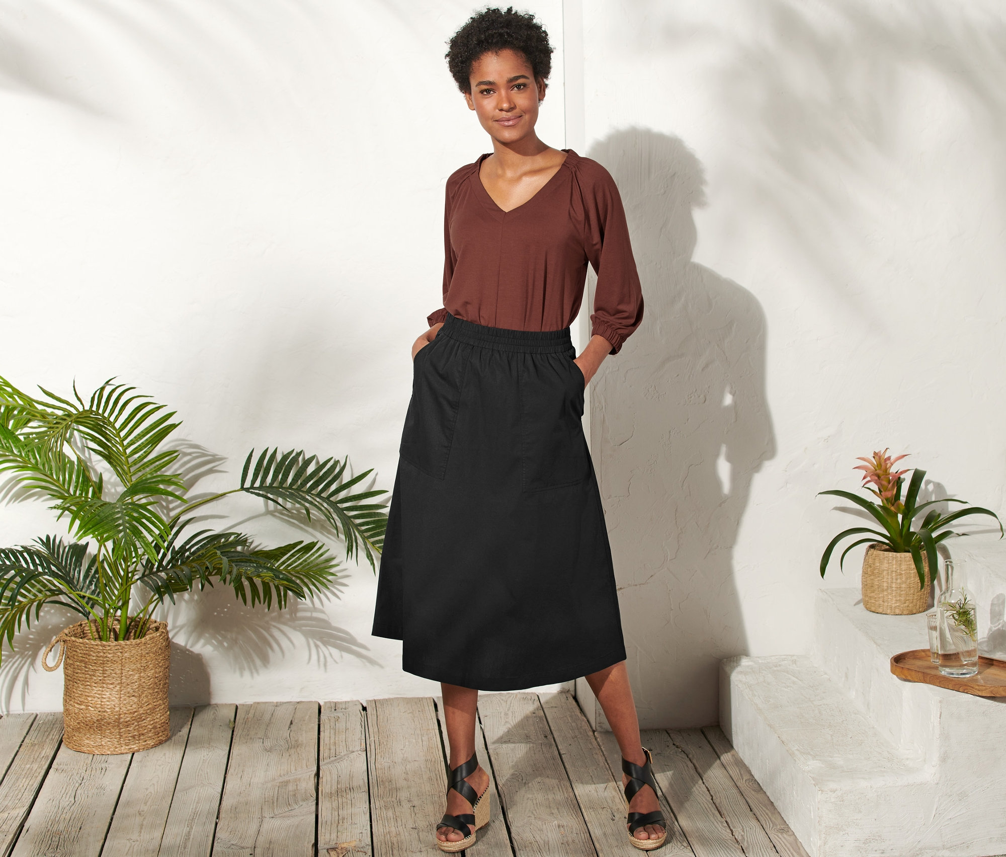 Kobieta pozuje w czarnej spódnicy z popeliny.