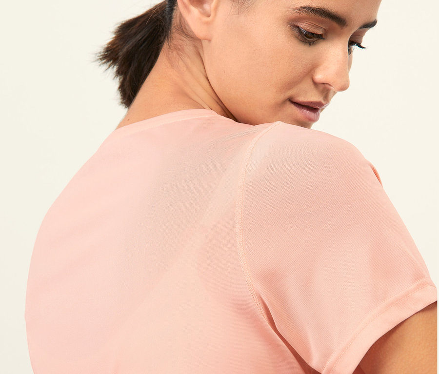 Zbliżenie na młodą kobietę o ciemnych włosach w różowej koszulce sportowej.