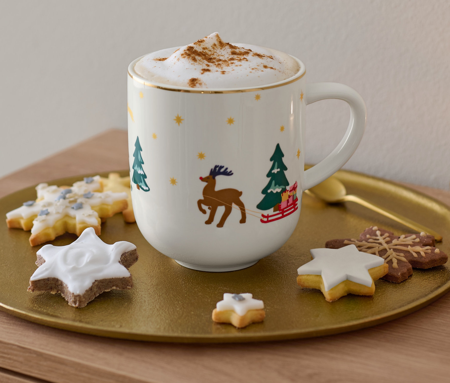 Na złotej tacy stoi duży kubek ze złotym zdobieniem, cappuccino i ciasteczka.