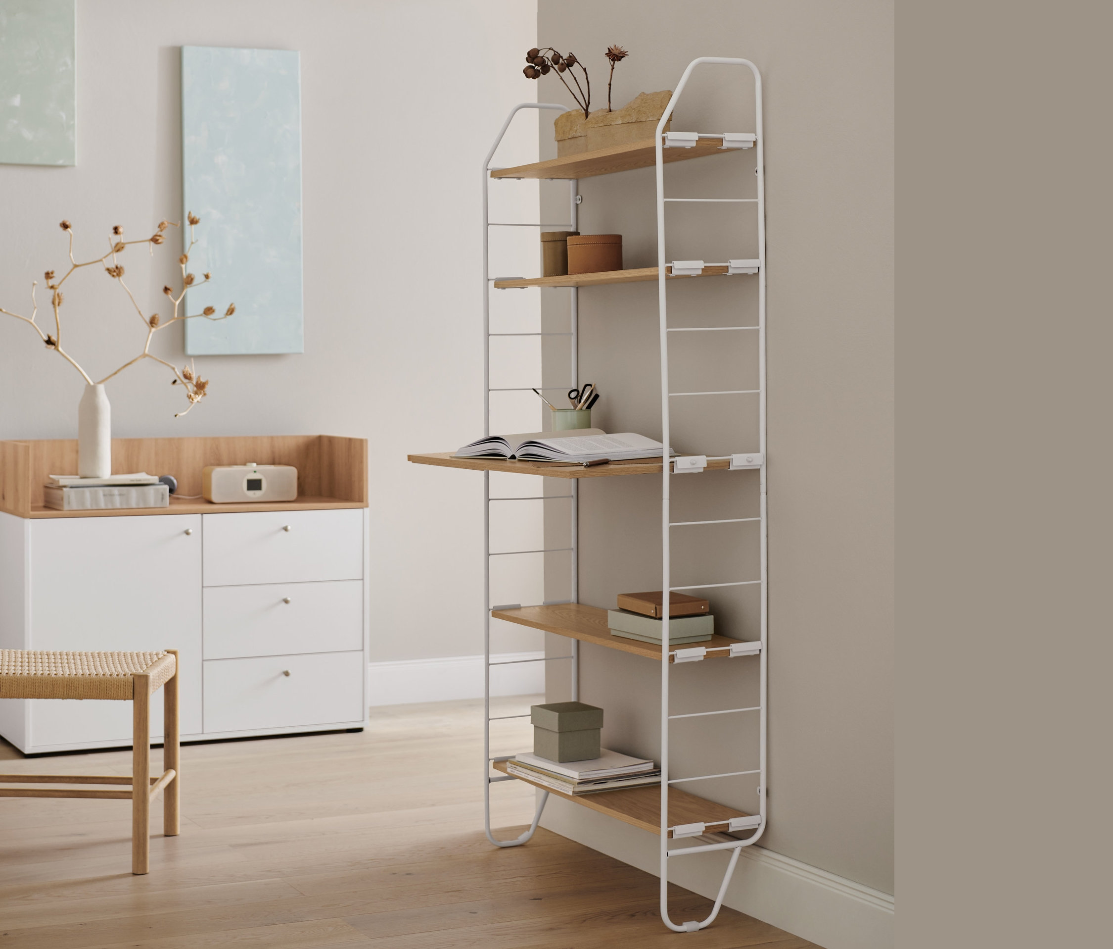 W pokoju stoi szafka z szufladami i drzwiami oraz regał ścienny z blatem.